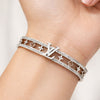 Silver bracelet with a brand logo on a wrist against a neutral background