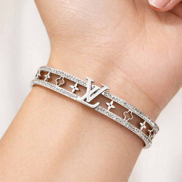 Silver bracelet with a brand logo on a wrist against a neutral background