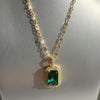 Gold necklace with a green gemstone pendant on a mannequin.